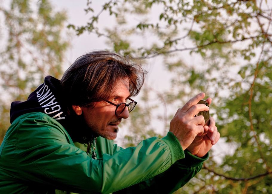 Shashi Tharoor Criticises Parliament Disruptions, Advocates for Debate A man in a green jacket capturing nature on his smartphone in Tirana, Albania.