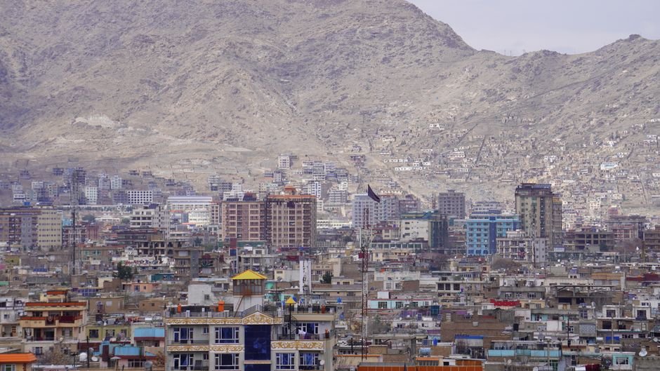 Afghanistan: Grenade Attack Near Kabul School Injures Multiple Children A panoramic view of Kabul city with high-rise buildings set against a mountainous backdrop.