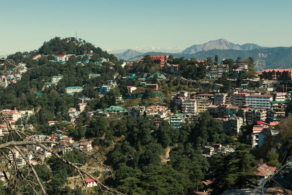 Himachal Pradesh: Needle Sharing Contributes to 19% of HIV Cases A picturesque view of a hill town surrounded by lush greenery and majestic mountains in the background.