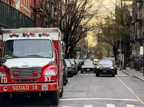A red fire truck from FDNY Squad 18 on a tree-lined street in New York City.