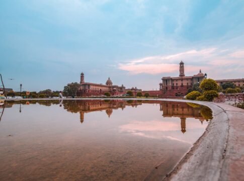 A serene reflection of Rashtrapati Bhavan in a water pond during a vibrant sunset.