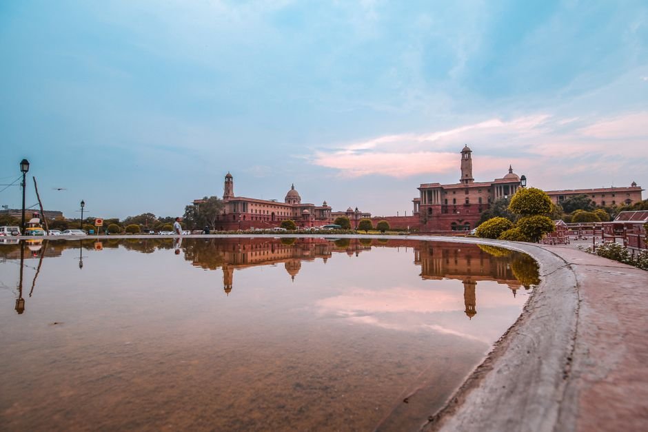 Delhi Cabinet Approves Draft Ease of Doing Business Bill Aiming for Simplified Procedures A serene reflection of Rashtrapati Bhavan in a water pond during a vibrant sunset.