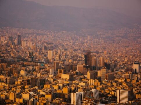 A sprawling view of Tehran's urban landscape with mountains in the background at sunset. A sprawling view of Tehran's urban landscape with mountains in the background at sunset.