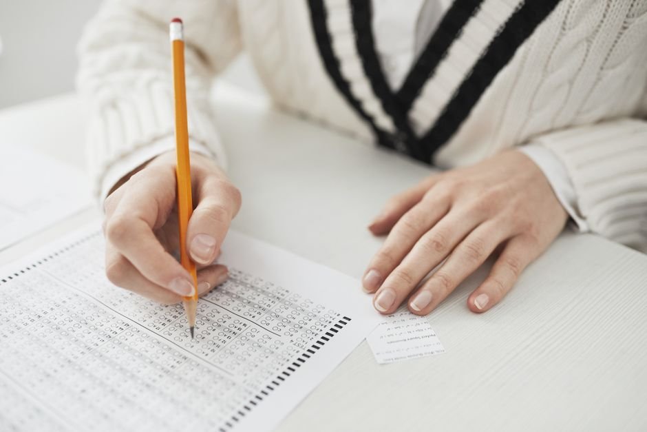 India: NTA Releases Provisional UGC-NET Answer Keys for 84 Subjects, Challenge Window Open A student writing answers on a multiple-choice exam sheet at a desk.