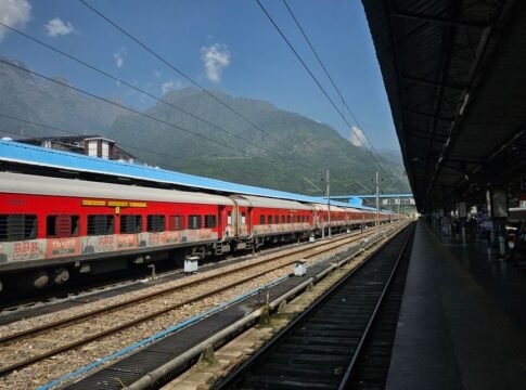 A vibrant red train at an outdoor station with scenic mountain backdrop, ideal for travel themes. A vibrant red train at an outdoor station with scenic mountain backdrop, ideal for travel themes.