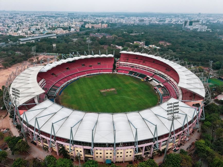Jammu and Kashmir’s Sher-i-Kashmir Stadium Eyed for Irani Cup 2026 Aerial photograph of a large, empty sports stadium surrounded by greenery and urban landscape.