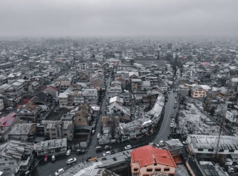 Aerial view of snowy Srinagar cityscape, showcasing rooftops and winding roads in winter. Aerial view of snowy Srinagar cityscape, showcasing rooftops and winding roads in winter.