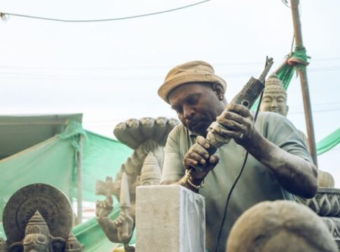 An artisan skillfully carves a stone statue in an outdoor workshop setting. An artisan skillfully carves a stone statue in an outdoor workshop setting.
