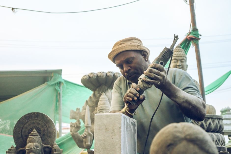 Jammu and Kashmir Artisans Honored with National Handloom Awards An artisan skillfully carves a stone statue in an outdoor workshop setting.