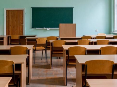 An empty classroom featuring wooden desks, chairs, and a large green chalkboard. An empty classroom featuring wooden desks, chairs, and a large green chalkboard.