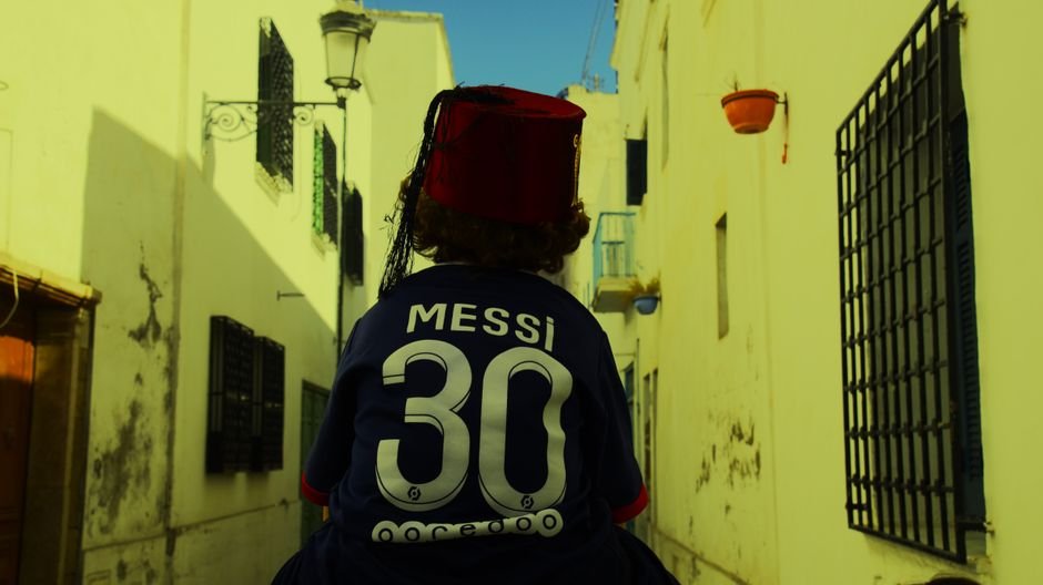 Lionel Messi Announces Retirement from Argentina National Team Back view of a person on a Tunis street wearing a fez and Messi jersey.