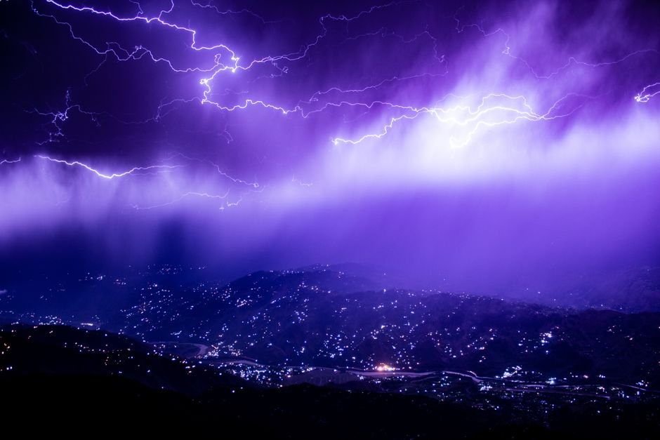 Jammu and Kashmir Braces for Rain, Heavy Showers Forecasted Captivating lightning storm over Muzaffarabad with a vivid purple sky, lighting up the mountains at night.