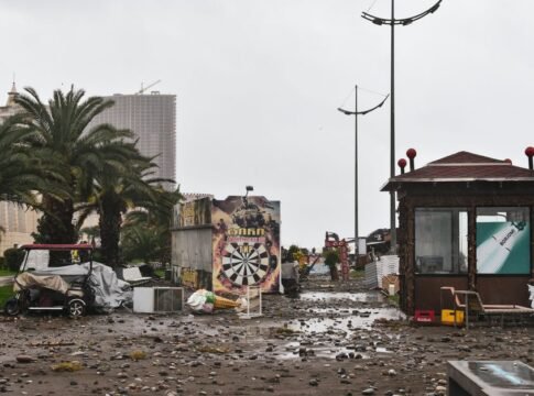 City street filled with storm debris and damaged structures under a cloudy sky. City street filled with storm debris and damaged structures under a cloudy sky.