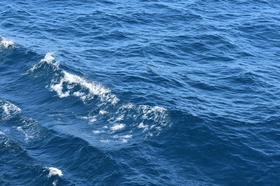 Dramatic Rescue in Remote Pacific Highlights Maritime Peril and Ingenuity Close-up view of dynamic ocean waves and blue sea with white caps on a sunny day.