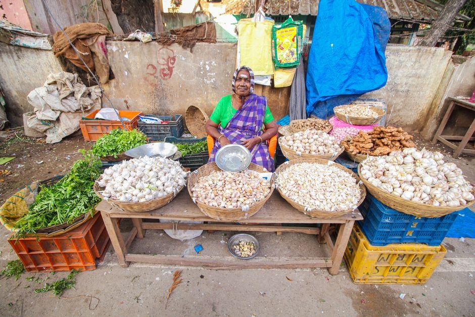 Tamil Nadu Finance Minister Outlines Two-Year Path to Fiscal Prudence Colorful street market scene of a senior vendor selling vegetables in Cumbum, India.