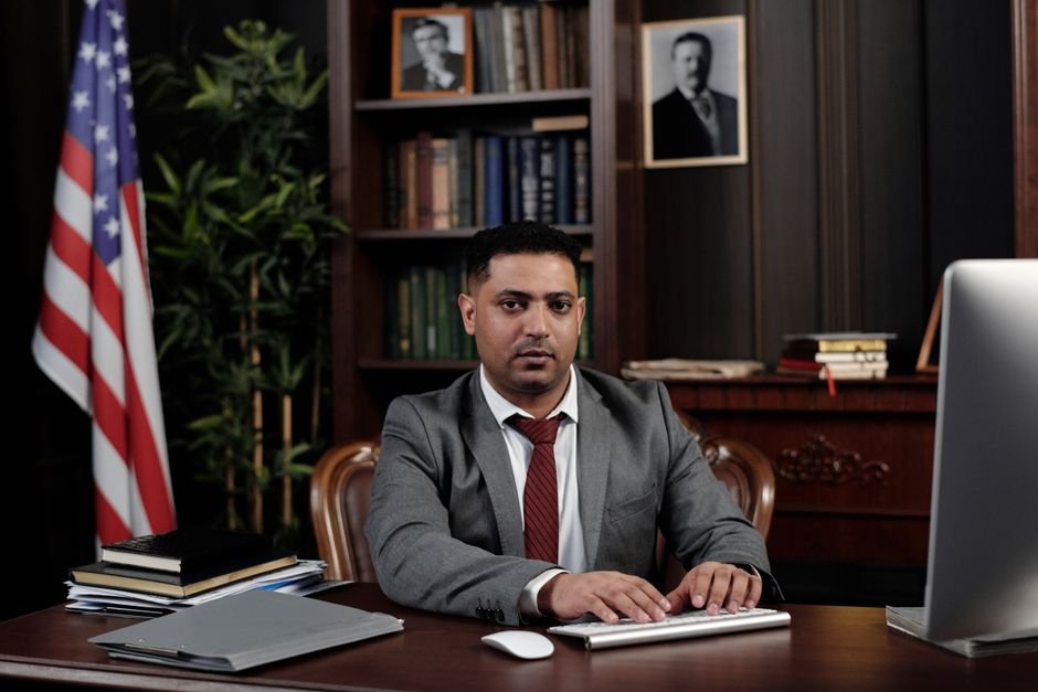 West Bengal: Former Deputy Speaker Ashis Banerjee Found Dead at Party Office Corporate professional sitting at desk with American flag in office.