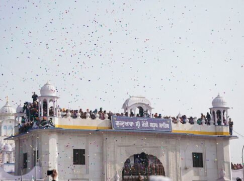 Crowds gather at a classic dome for a traditional festival with colorful confetti in the air.
