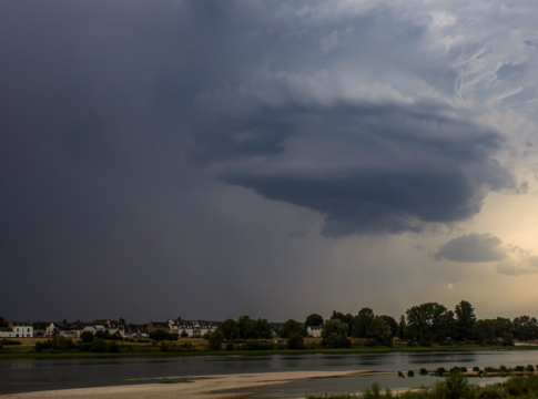 Dark supercell cloud formation over a city skyline with dramatic lighting, showcasing powerful weather.