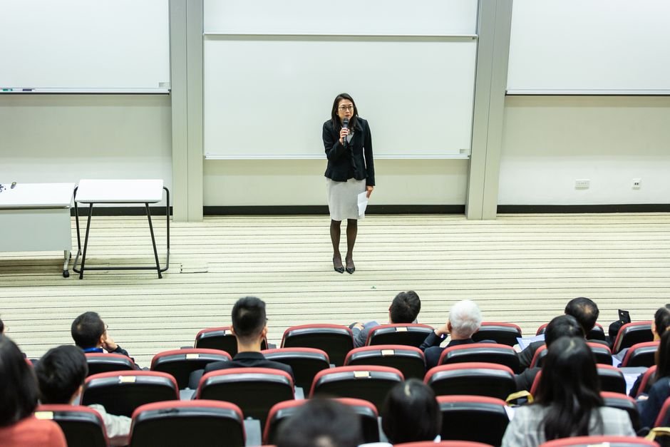 Punjab: Charitable Society Empowers Students Pursuing Higher Education in Patiala Female speaker presenting to an audience in a modern auditorium setting.
