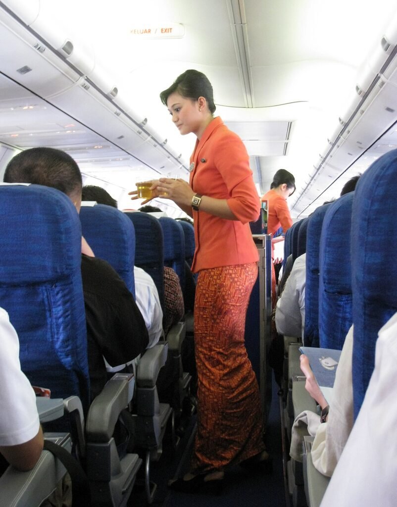 Garuda Indonesia flight attendants serving refreshment. The new in-flight costumes for Garuda Indonesia stewardesses are inspired by the traditional Kartini-styled kebaya for the upper torso with bat…