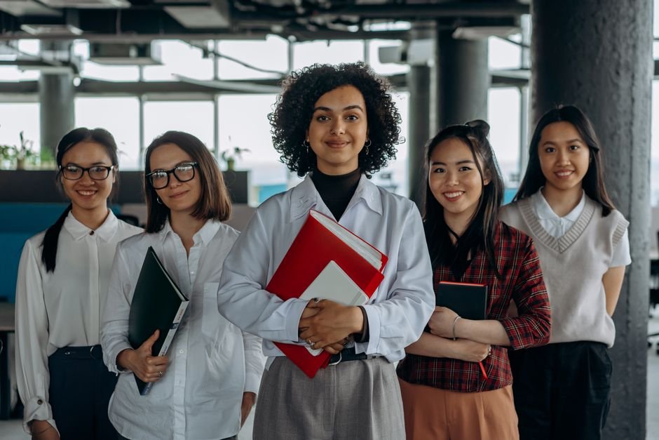 Jammu and Kashmir: Indian Youth Chart New Career Trajectories Beyond Traditional Paths Group of diverse women colleagues smiling in a modern office setting, holding documents.