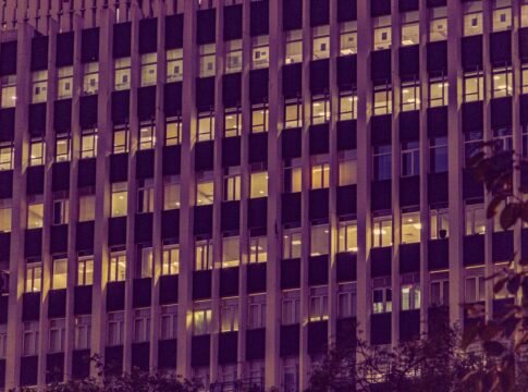 Illuminated urban office building facade at night in New Delhi, showcasing modern architecture with glowing windows. Illuminated urban office building facade at night in New Delhi, showcasing modern architecture with glowing windows.