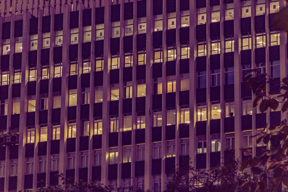 Illuminated urban office building facade at night in New Delhi, showcasing modern architecture with glowing windows.