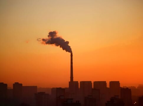 Industrial smokestack emitting smoke during sunset, highlighting environmental impact. Industrial smokestack emitting smoke during sunset, highlighting environmental impact.