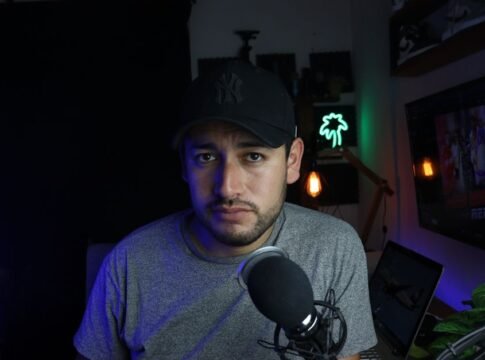 Male content creator in a home studio setup with microphone and soft lighting.