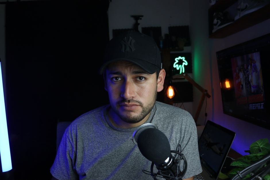 Iranian YouTube Show Navigates Sensitive Topics, Posing Questions Unspoken in Public Male content creator in a home studio setup with microphone and soft lighting.