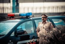 Kishtwar Police Trace Two Missing Girls, Reunite Them With Families Male in uniform standing near patrol car with flashing lights and looking away