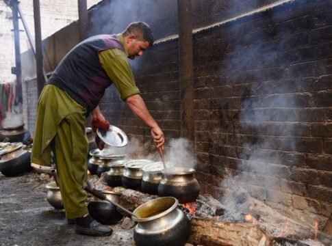 Man stirring pots over a fire in a traditional Srinagar kitchen. Man stirring pots over a fire in a traditional Srinagar kitchen.