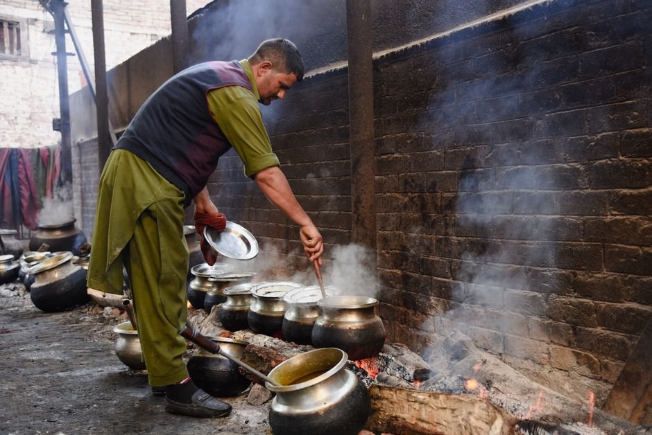 Jammu and Kashmir: Food Safety Department Vigilant Over Amarnath Yatra Pilgrim Meals Man stirring pots over a fire in a traditional Srinagar kitchen.