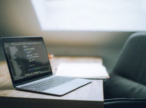 Open laptop displaying code on desk in bright, modern office setting. Ideal for tech and remote work context. Open laptop displaying code on desk in bright, modern office setting. Ideal for tech and remote work context.