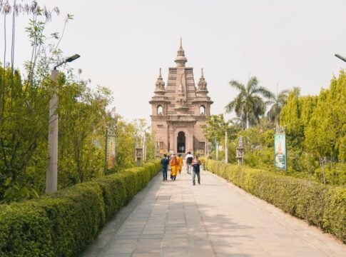 People walking on a garden pathway towards an ancient temple with lush greenery. People walking on a garden pathway towards an ancient temple with lush greenery.