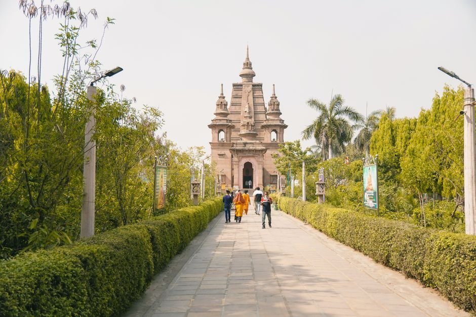 Punjab’s Virsa Vihar in Jalandhar Faces Neglect, Cultural Activities Decline People walking on a garden pathway towards an ancient temple with lush greenery.