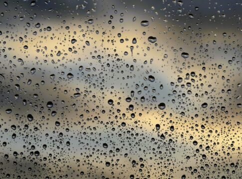 Raindrops scattered on a window pane with a soft, cloudy sky in the background, creating a moody atmosphere. Raindrops scattered on a window pane with a soft, cloudy sky in the background, creating a moody atmosphere.