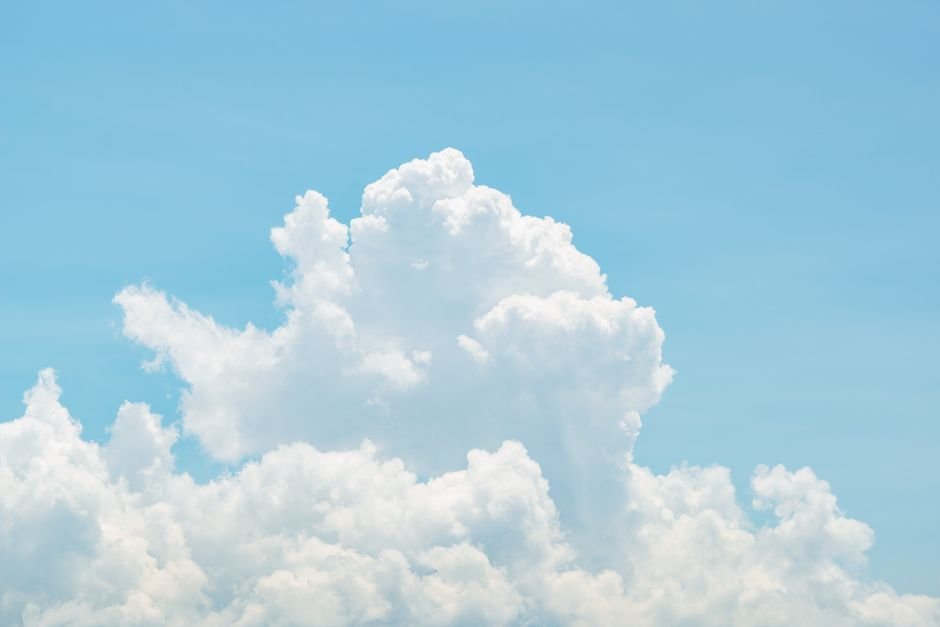 Serene image of fluffy white clouds against a bright blue sky, perfect for depicting calm and nature.