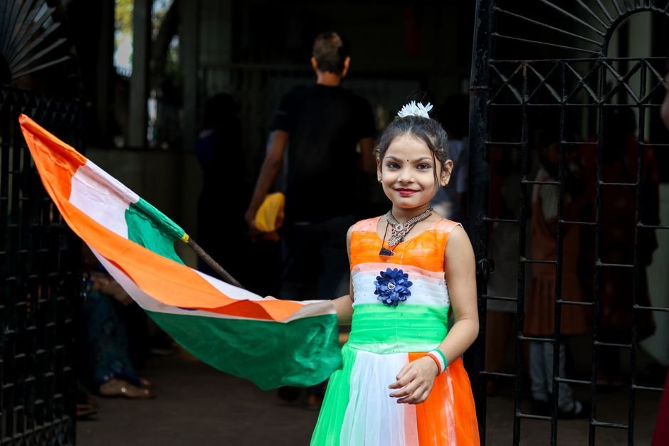 Srinagar: Full Dress Rehearsal Held at Bakshi Stadium for Independence Day Smiling girl in tricolor dress holds Indian flag during Independence Day celebration in India.