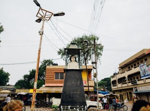 Street view of a bust sculpture in an Indian town square, surrounded by buildings and people. Street view of a bust sculpture in an Indian town square, surrounded by buildings and people.