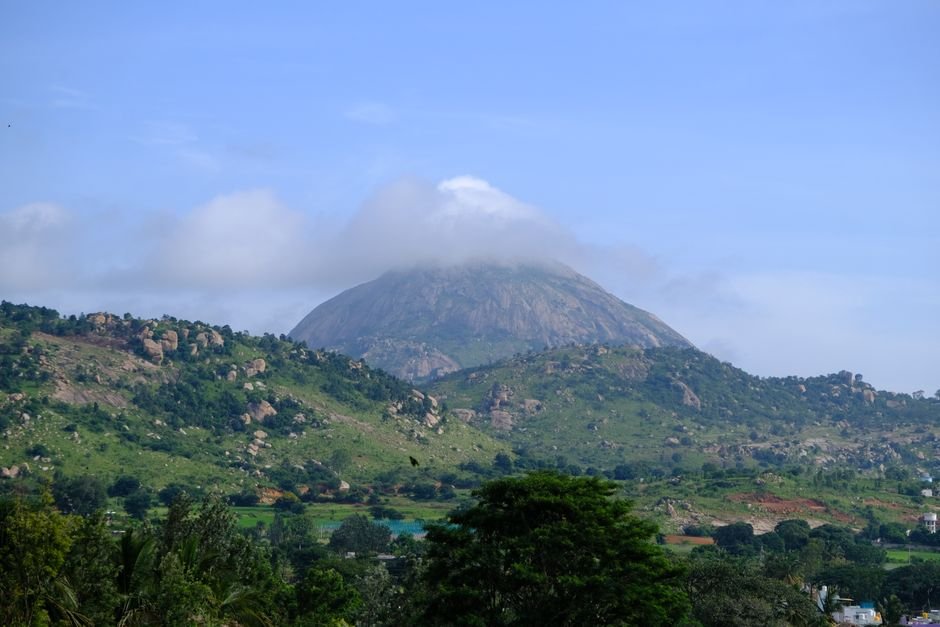 Stunning landscape of Nandi Hills in Karnataka, India, featuring a cloud-capped peak surrounded by lush greenery.