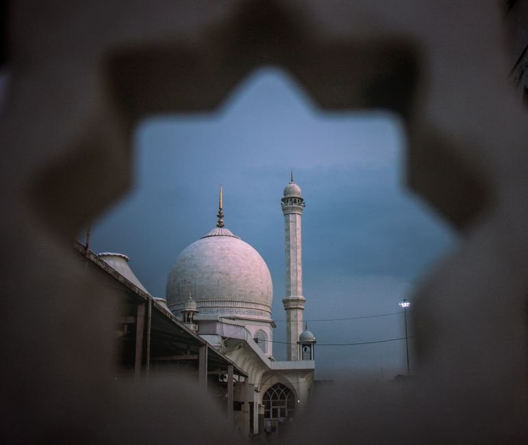 Stunning twilight view of Dargah Hazratbal Mosque in Srinagar seen through a decorative frame.
