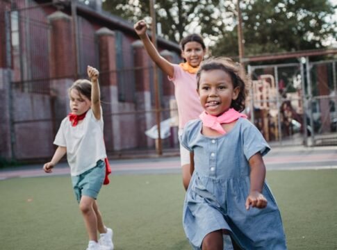 Three children enjoying a playful competition at an outdoor playground, showcasing motion and joy.