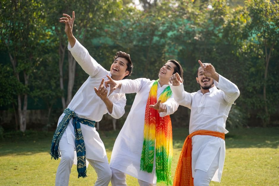 Uttar Pradesh: Samajwadi Party’s Outreach to Brahmins Faces Scrutiny as Community Seeks Tangible Actions Three men in traditional clothing celebrate outdoors with energetic joy and colorful scarves.