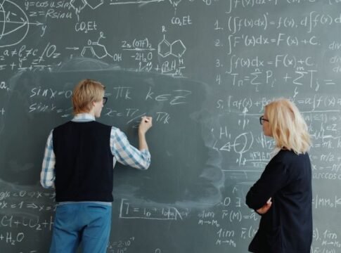 Two professors collaborate on solving complex math equations in classroom. Two professors collaborate on solving complex math equations in classroom.