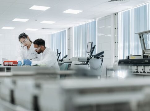 Two scientists working in a high-tech laboratory setting, wearing protective eyewear and gloves. Two scientists working in a high-tech laboratory setting, wearing protective eyewear and gloves.