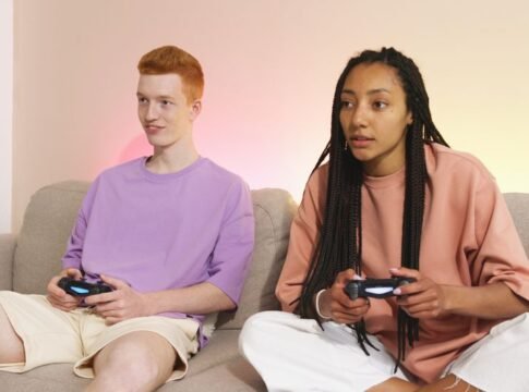Two young adults enjoying video gaming on a comfortable sofa at home. Two young adults enjoying video gaming on a comfortable sofa at home.