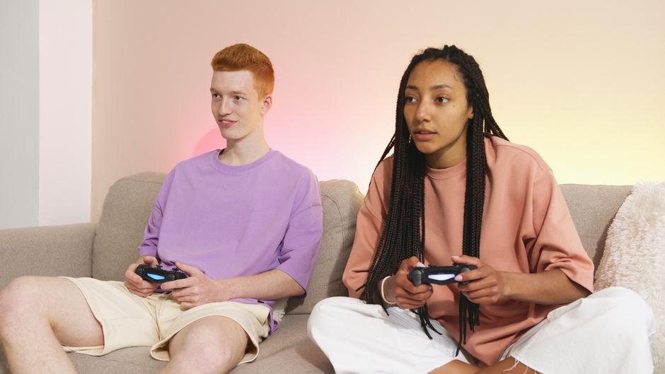 Two young adults enjoying video gaming on a comfortable sofa at home.