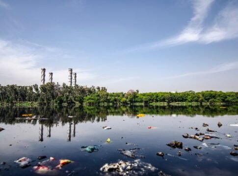 View of a polluted river reflecting factory emissions under a clear sky in India. View of a polluted river reflecting factory emissions under a clear sky in India.