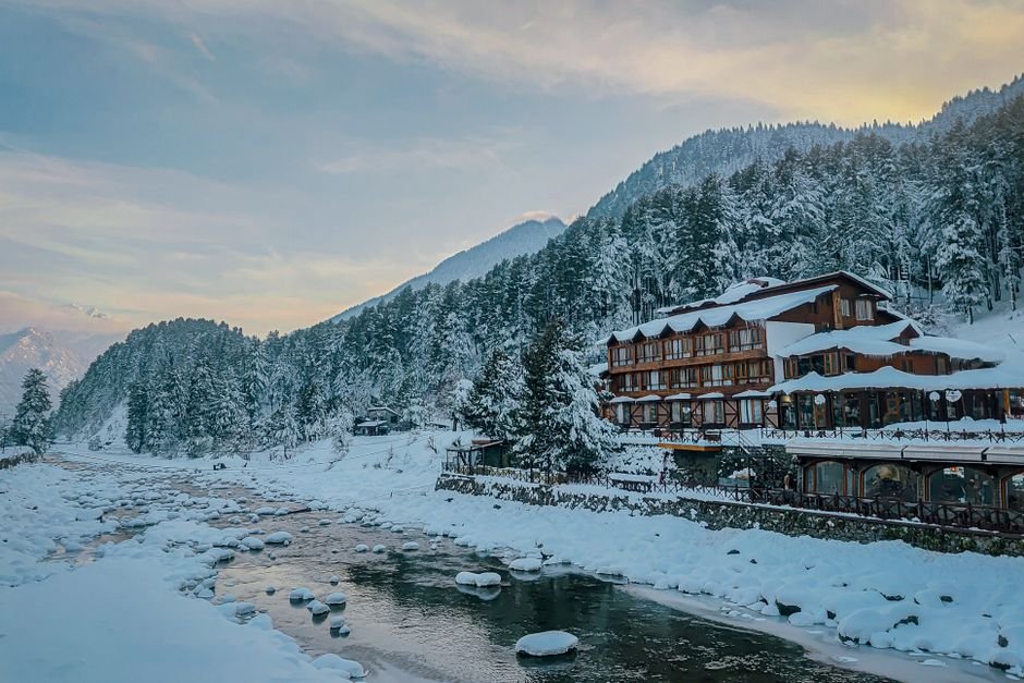 A beautiful winter scene of Pahalgam, Kashmir with snow-covered landscapes and serene river view.